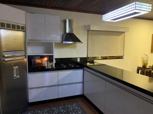 a kitchen with white cabinets and a stainless steel refrigerator at Guarda do Embaú Morretes in Guarda do Embaú