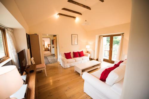 a living room with two white couches and red pillows at Whitley Coach House in Whitley