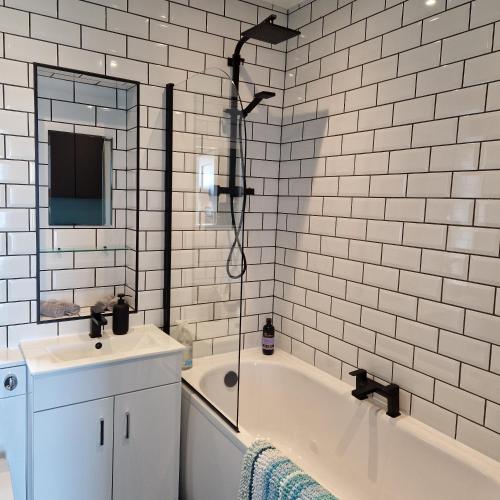 a bathroom with a tub and a sink and a shower at Stylish bungalow with complimentary breakfast on the first morning in Lancing