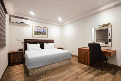 1 dormitorio con cama, escritorio y silla en Nicotel Apartments, en Lekki