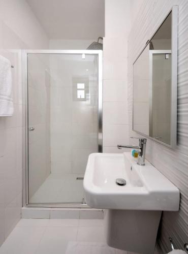 a white bathroom with a sink and a shower at Nicotel Apartments in Lekki