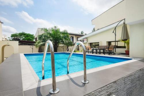 a swimming pool with metal hand rails next to a house at Nicotel Apartments in Lekki