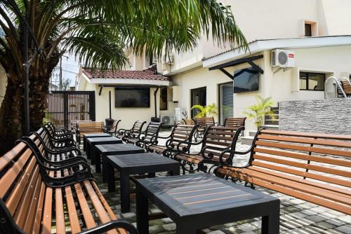 Nicotel Apartments في ليكى: صف من المقاعد والطاولات الخشبية أمام المبنى