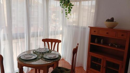 uma mesa com pratos e copos numa sala com uma janela em APARTAMENTO PLAYA AZUL em Rincón de la Victoria