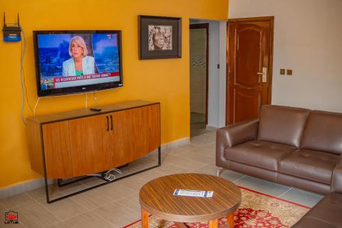 a living room with a couch and a flat screen tv at Mayombe Arena Hotel in Pointe-Noire