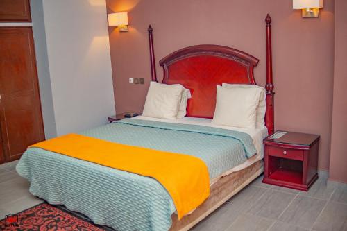 a bedroom with a large bed with a red headboard at Mayombe Arena Hotel in Pointe-Noire