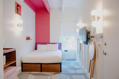 a small room with a bed and a pink wall at The Gallatin in Nashville