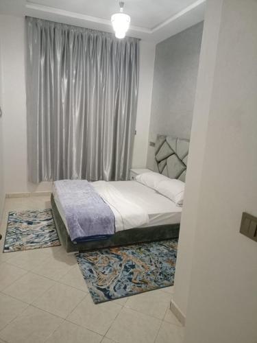 a bedroom with a bed with a window and a rug at أكادير حي السلام in Agadir
