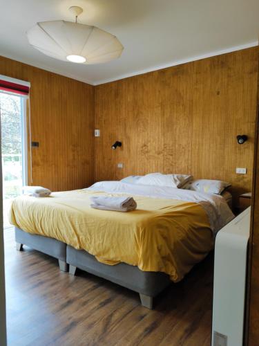 uma cama grande num quarto com paredes de madeira em Casa en el Campo Paine em Maipo