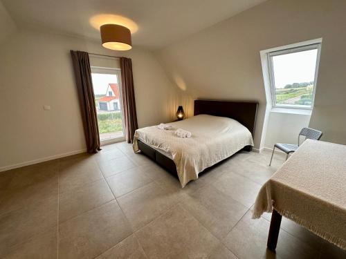 een slaapkamer met een bed en een groot raam bij La Lumineuse in Tardinghen
