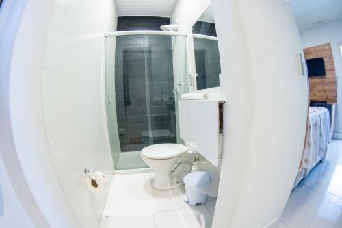 a white bathroom with a toilet and a shower at Pousada Veneza in Itabuna