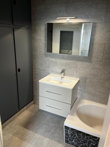 a bathroom with a sink and a tub and a mirror at Gîte Familie in Meyenheim