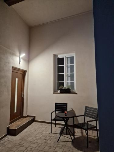 Zimmer mit 2 Stühlen, einem Tisch und einem Fenster in der Unterkunft Apartmán Anežka 3 s vířivou vanou in Jičín