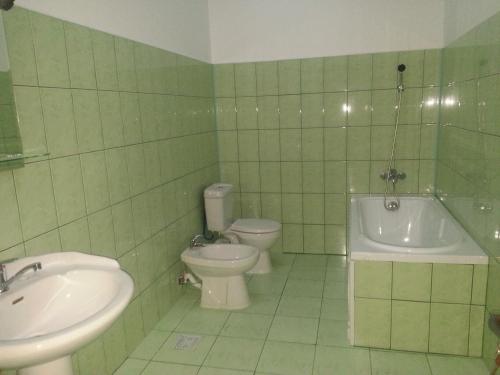 a green tiled bathroom with a toilet and a sink at Casa Rustica in Focşani