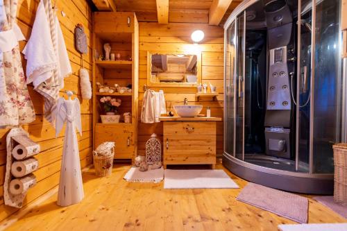 baño en una cabaña de madera con lavabo y ducha en Roubenka Bruno, en Karlovy Vary