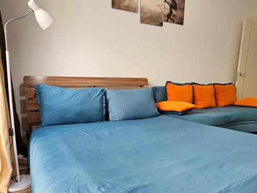 Cama azul con almohadas de color naranja y sofá en Abay 130 en Almaty