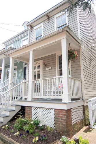 a house with a porch with a white railing at Cozy 2br home w/ parking in downtown Annapolis in Annapolis