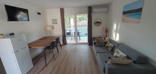 - un salon avec un canapé, une table et un réfrigérateur dans l'établissement Fiori Di Cala Rossa Appartement T3 dans résidence hôtellière chez Virginie, à Lecci