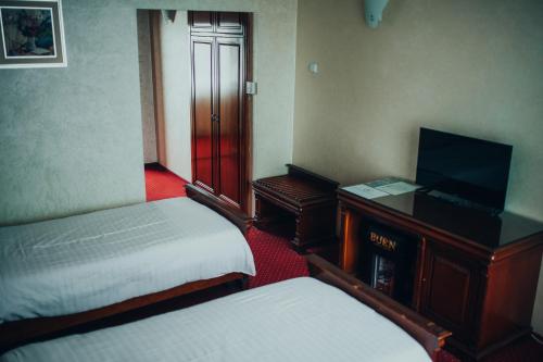 a hotel room with two beds and a television at Hotel Bavaria in Craiova