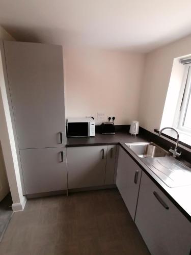 a small kitchen with a sink and a microwave at Apollo Avenue Apartment in Stony Stratford
