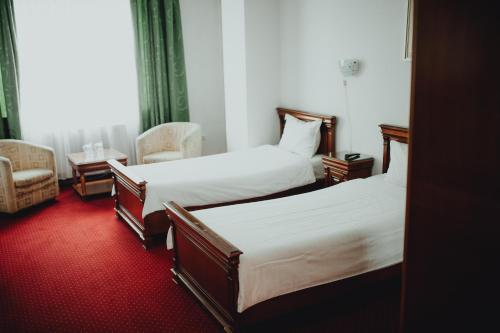 a hotel room with two beds and a chair at Hotel Bavaria in Craiova