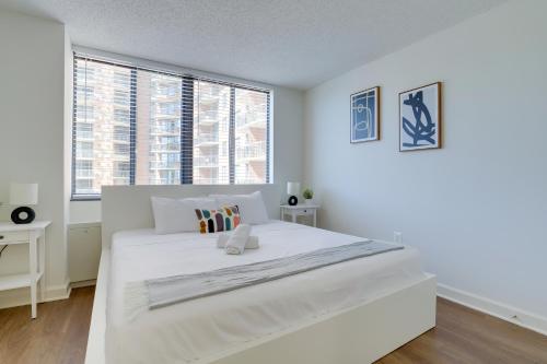 a white bedroom with a large white bed and windows at Unique Luxury Apt with Rooftop @Pentagon City in Arlington