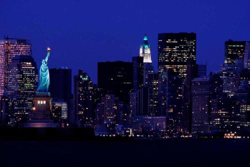 a city skyline with the statue of liberty at night at Westchester Marriott in Tarrytown