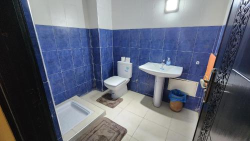 a blue tiled bathroom with a toilet and a sink at Résidence Belle Vue 6 in Marrakesh