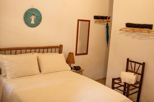 um quarto com uma cama, uma cadeira e um espelho em Suites da Loja Caraíva em Porto Seguro