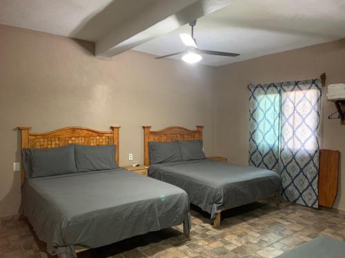 a bedroom with two beds and a ceiling fan at Bungalows Victoria in La Manzanilla