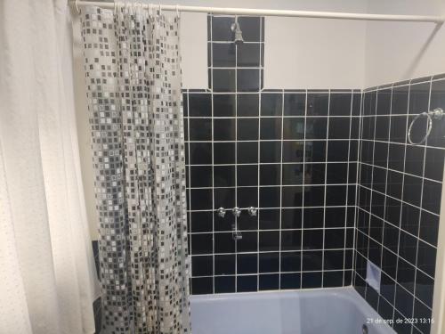 a bathroom with a black tiled shower curtain and a tub at Buenos Aires, CABA in Buenos Aires