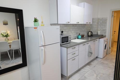 cocina blanca con nevera y mesa en דירת אירוח vip רק 5 דקות נסיעה מהים חלום של מקום, en Ashkelon