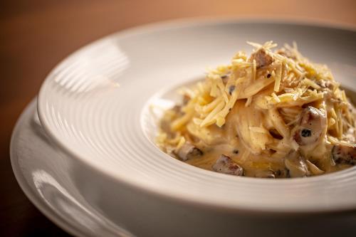 a white bowl of food with meat and cheese at Porto Pacuíba Hotel in Ilhabela