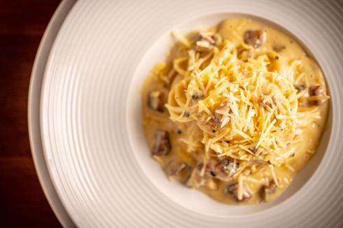a white plate with a bowl of soup with cheese at Porto Pacuíba Hotel in Ilhabela
