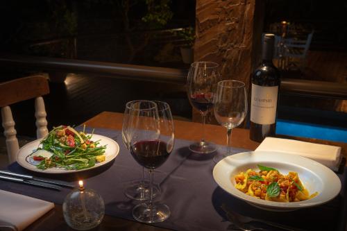 a table with two plates of food and wine glasses at Porto Pacuíba Hotel in Ilhabela