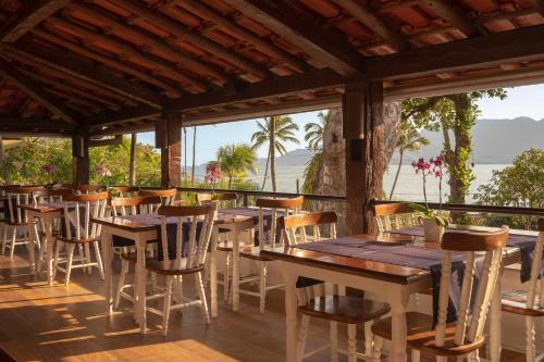 a restaurant with wooden tables and chairs on a deck at Porto Pacuíba Hotel in Ilhabela