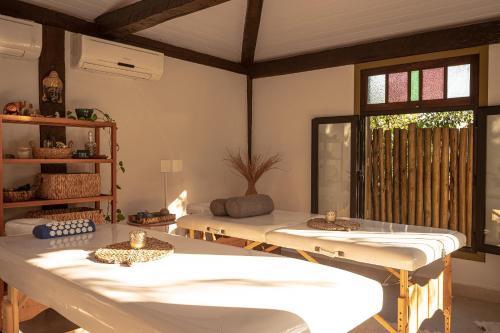 a room with two beds and a table and a window at Porto Pacuíba Hotel in Ilhabela
