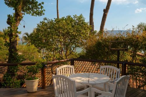 a table and chairs on a deck with a view of the ocean at Porto Pacuíba Hotel in Ilhabela
