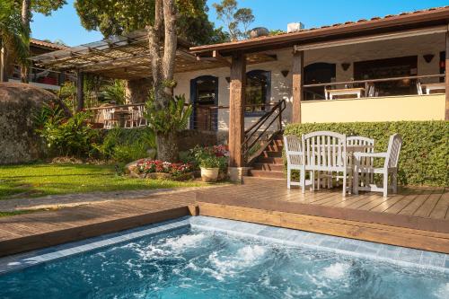 a house with a pool and a deck with two chairs at Porto Pacuíba Hotel in Ilhabela