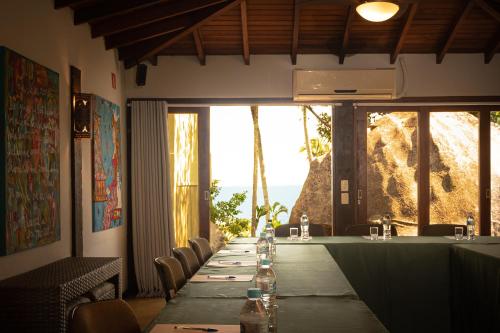 a long table in a restaurant with a long table with chairs at Porto Pacuíba Hotel in Ilhabela