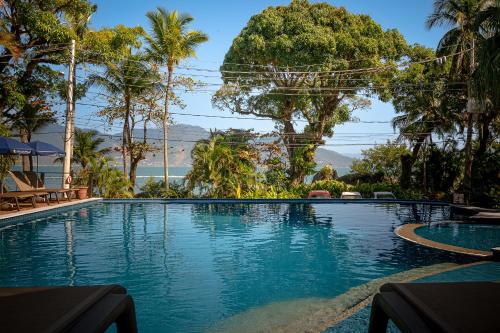 a swimming pool in a resort with palm trees at Porto Pacuíba Hotel in Ilhabela
