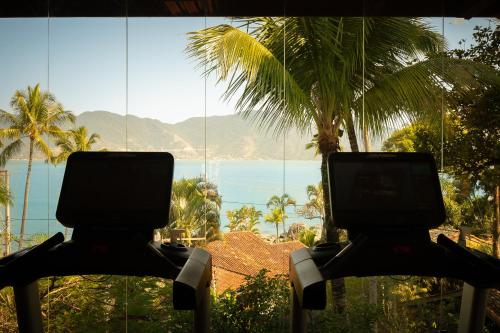 two chairs with a view of the ocean and palm trees at Porto Pacuíba Hotel in Ilhabela