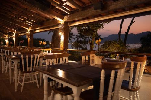 a restaurant with tables and chairs and a view of the ocean at Porto Pacuíba Hotel in Ilhabela