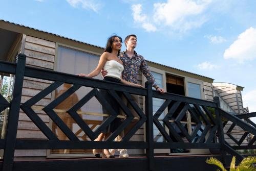 un homme et une femme debout sur une clôture devant une maison dans l'établissement Lavish Country Retreat 30mins Taxi Ride From West London, à Chessington