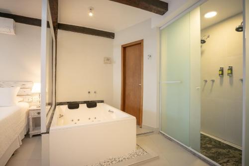 a bathroom with a tub and a bed and a shower at Porto Pacuíba Hotel in Ilhabela
