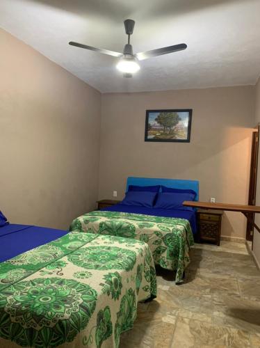 a bedroom with two beds and a ceiling fan at Bungalows Victoria in La Manzanilla