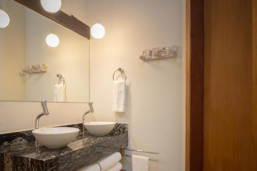 a bathroom with two sinks and a large mirror at Porto Pacuíba Hotel in Ilhabela