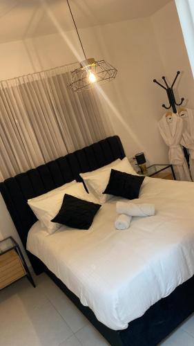 a bedroom with a large white bed with black pillows at מצפור הכנרת- דירת גן לאירוח in Tiberias