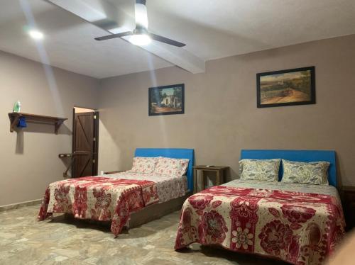 a bedroom with two beds and a ceiling fan at Bungalows Victoria in La Manzanilla