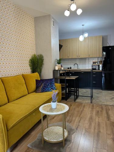 a living room with a yellow couch and a table at Apartament Alexa na Tatarskiej A in Przemyśl